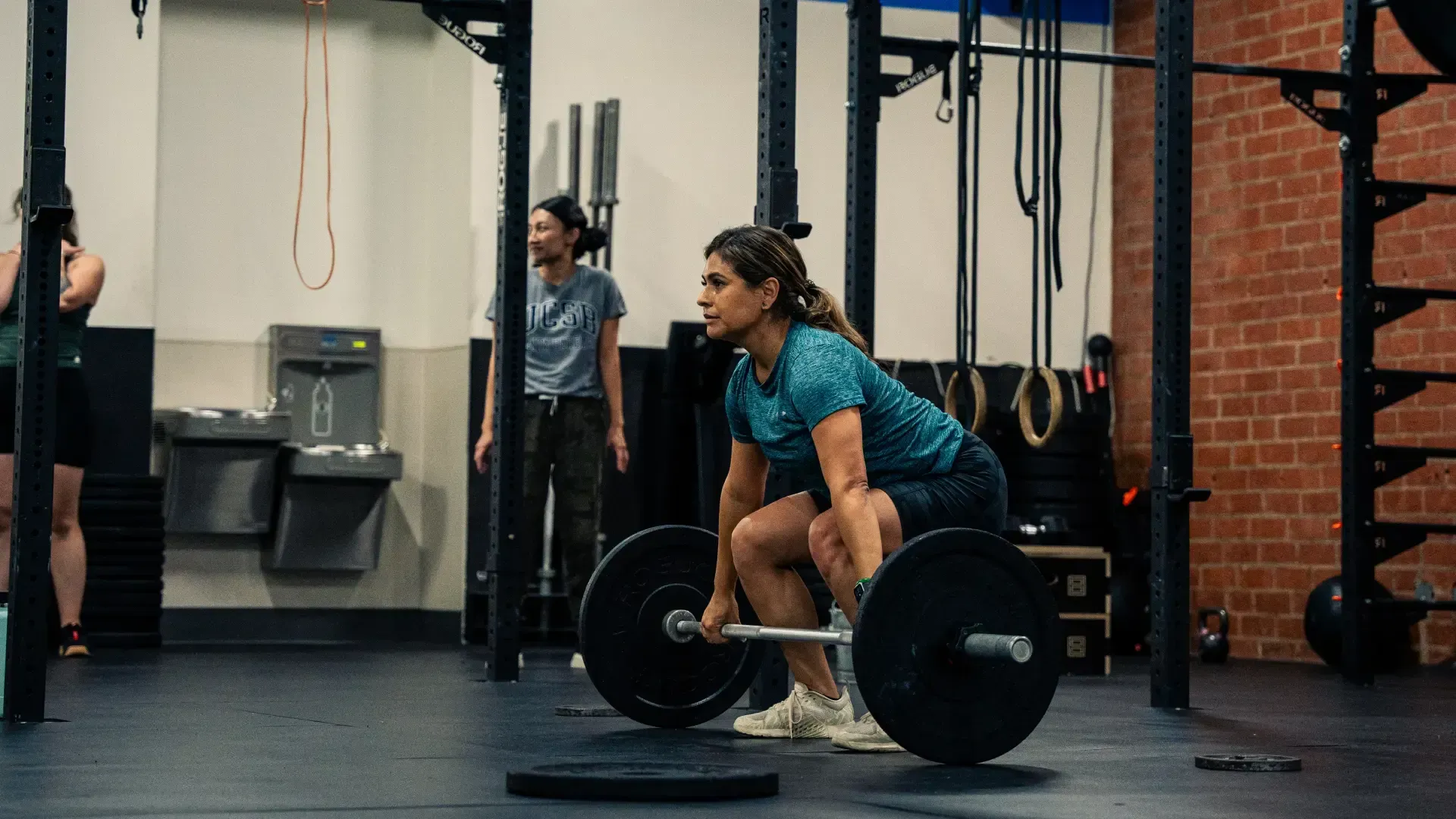 CrossFit 626 members pressing weighted bars overhead during a group class in San Marino